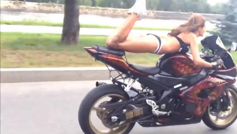 O femeie face acrobaţii pe motocicletă