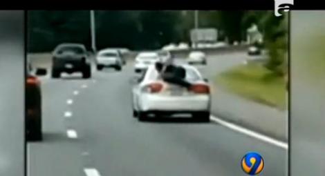 Cascadorie în trafic! Un bărbat circulă pe capota unei maşini, pe o autostradă aglomerată din SUA