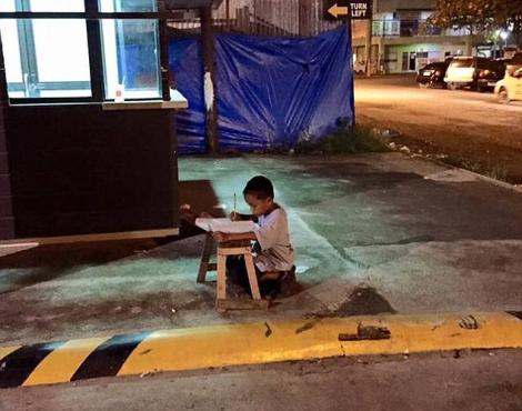 Un copil își face temele în stradă, la lumina diferitelor magazine! O poveste de viață emoționantă și fotografie ce nu mai are nevoie de cuvinte!