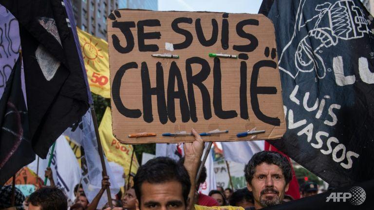 "Asasinul este &icirc;n continuare liber". Dumnezeu cu m&acirc;inile &icirc;ns&acirc;ngerate, pe coperta Charlie Hebdo, la un an de la atacul terorist