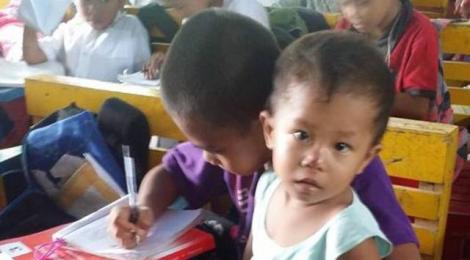 Un puști sărac de nouă ani nu vrea să renunțe la școală, așa că își ține frățiorul mai mic în brațe, în timp ce scrie lecțiile!