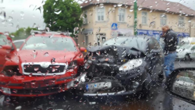 DE APLAUDAT! Un polițist din Brașov, fotografiat în timp ce mătură carosabilul, pe ploaie, după un accident, pentru a putea da drumul circulației