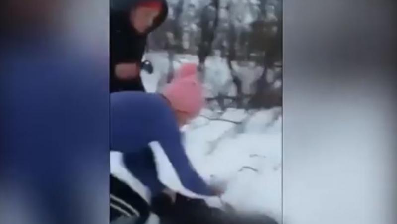 Bătaie cruntă! O elevă este călcată în picioare de alte două colege, pe un câmp. Trântită în zăpadă și lovită sistematic, fata plânge de durere: 