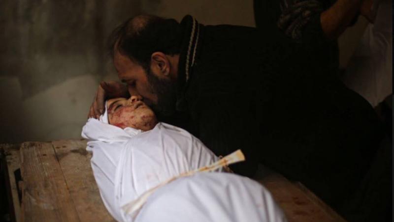 Siria, mormântul copilăriei. Imaginea care-ți taie respirația: Un tată își cară copilul mort, într-un cearșaf. Nu merg acasă, ci la groapă