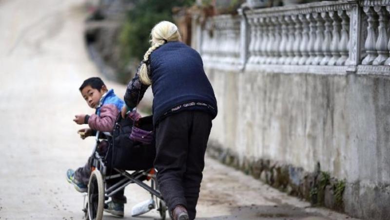 O bunicuță de 76 de ani, înghite, zilnic, 24 de kilometri, împingând scaunul cu rotile al nepoțelului de 9 ani. ”Trebuie să meargă la școală. Asta e pe primul loc”