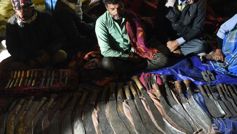 Un fierar își arată lamele de sacrificiu de vânzare în apropierea unei incinte de bivoli
