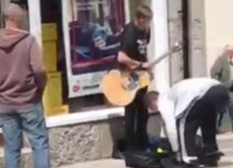 Momentul scandalos în care doi hoți fură bani de la un nevăzător care cânta la chitară, pe stradă! O cameră de supraveghere a filmat tot! Video