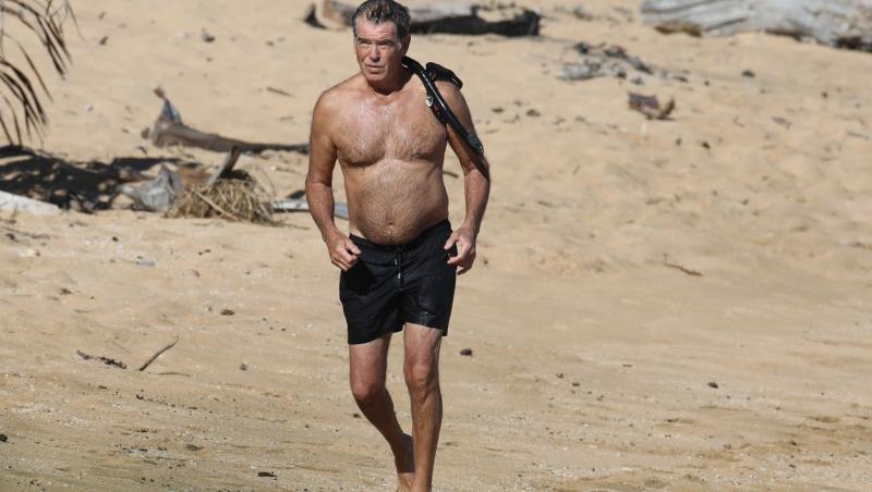 Pierce Brosnan, surprins la bustul gol pe plajă, purtând pe umăr echipamentul de scufundări