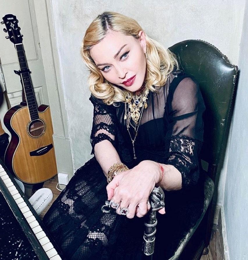 Madonna este așezată pe scaun, cu o chitară lângă ea