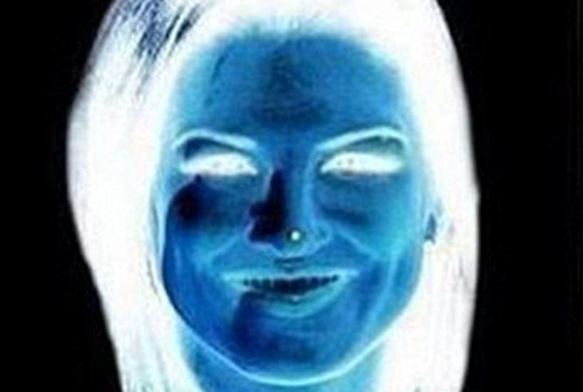 O imagine editata cu filtru negative in care apare chipul unei femei, care are un punct alb pe nas
