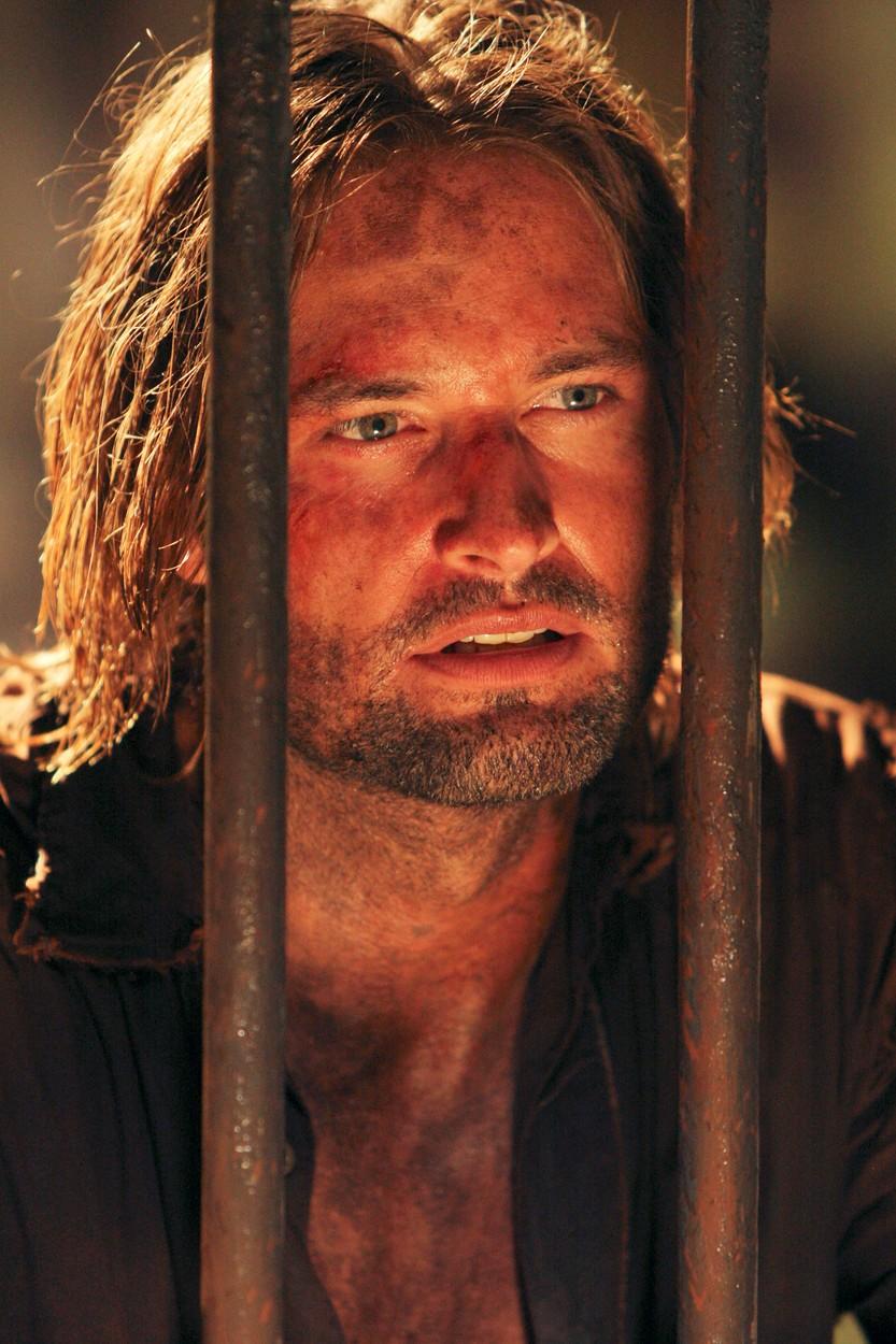 Josh Holloway, într-o scenă din Lost, uitându-se printre gratii (2004)