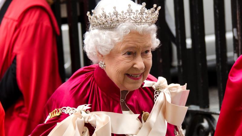 Regina Angliei poartă pe cap o coroană mare, strălucitoare