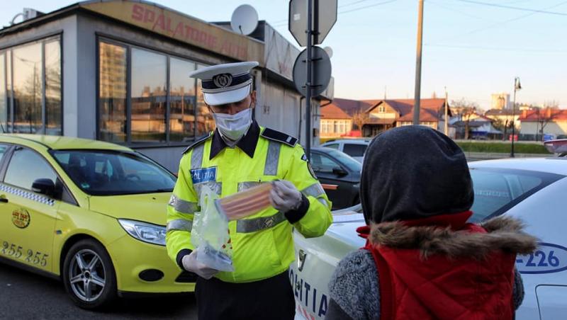 O femeie primește mască de protecție de la un polițist ieșean