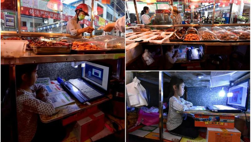 O fetiță își face temele sub taraba la care mama ei vinde pește