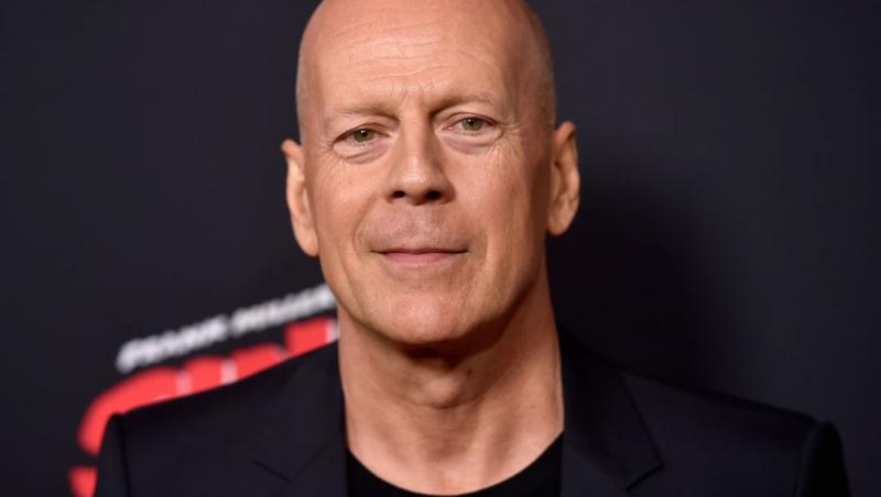 Bruce Willis pe covorul rosu intr-un costum negru