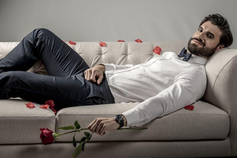 Imagine cu Andi Constantin, protagonistul emisiunii „Burlacul” de la Antena 1, stând întins pe o canapea și având un trandafir în mână
