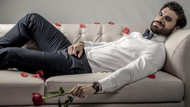 Imagine cu Andi Constantin, protagonistul emisiunii „Burlacul” de la Antena 1, stând întins pe o canapea și având un trandafir în mână