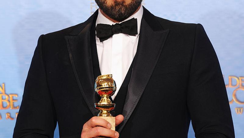 Ben Affleck imbracat la sacou negru si camasa alba, papion negru, tine in mana un trofeu