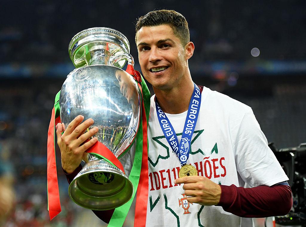 Cristiano Ronaldo cu un trofeu în mână și o medalie la gât