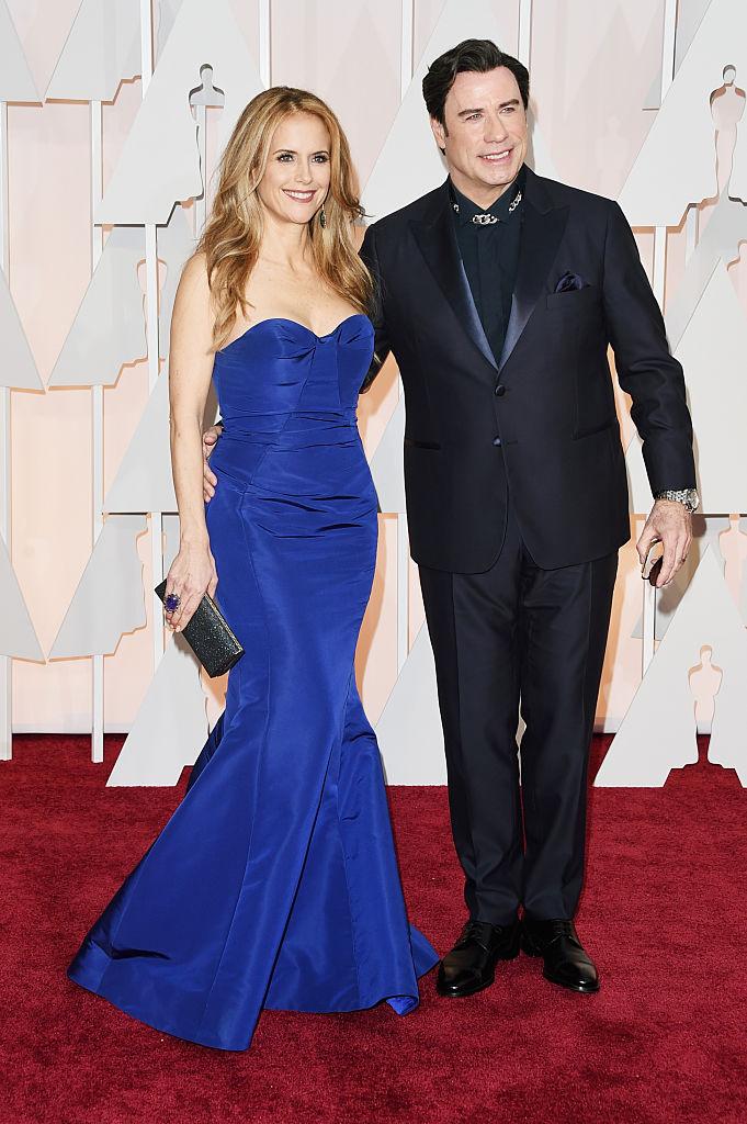John Travolta si soția lui pe covorul rosu, el este imbracat in negru, iar ea intr-o rochie albastra