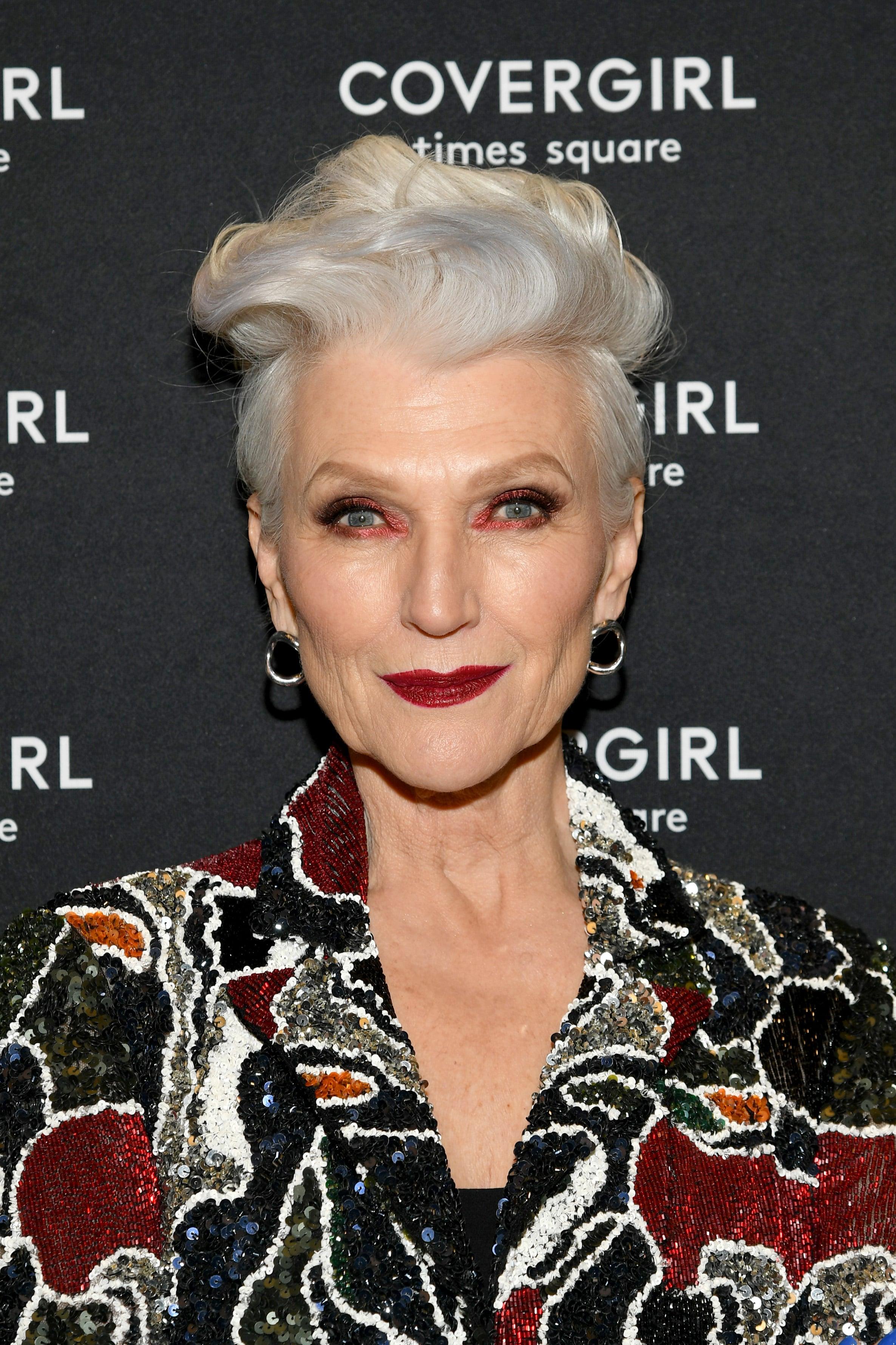 Maye Musk, covor rosu, par alb, bluza cu rosu, argintiu si negru