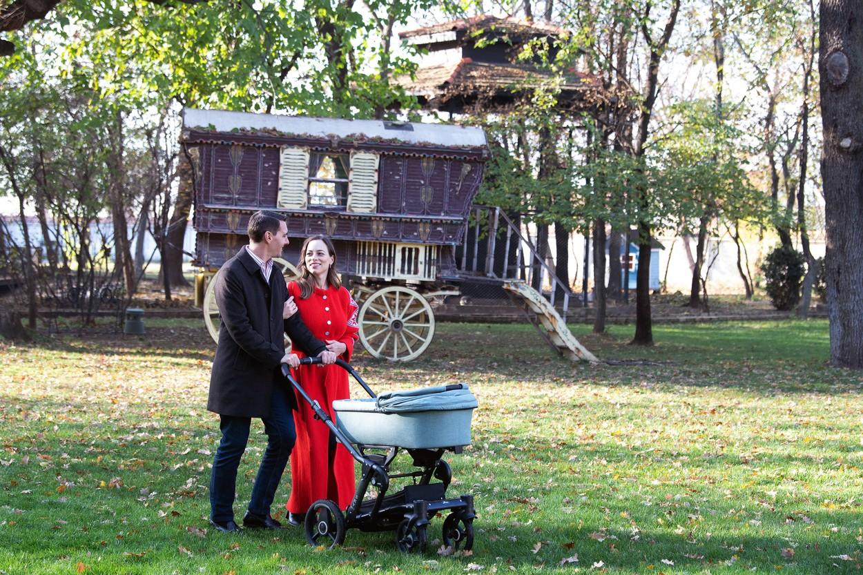 Fostul Principe Nicolae, purtând sacou negru, împreună cu soția lui Alina Binder, purtând o rochie roșie și cu fetița lor, în cărucior