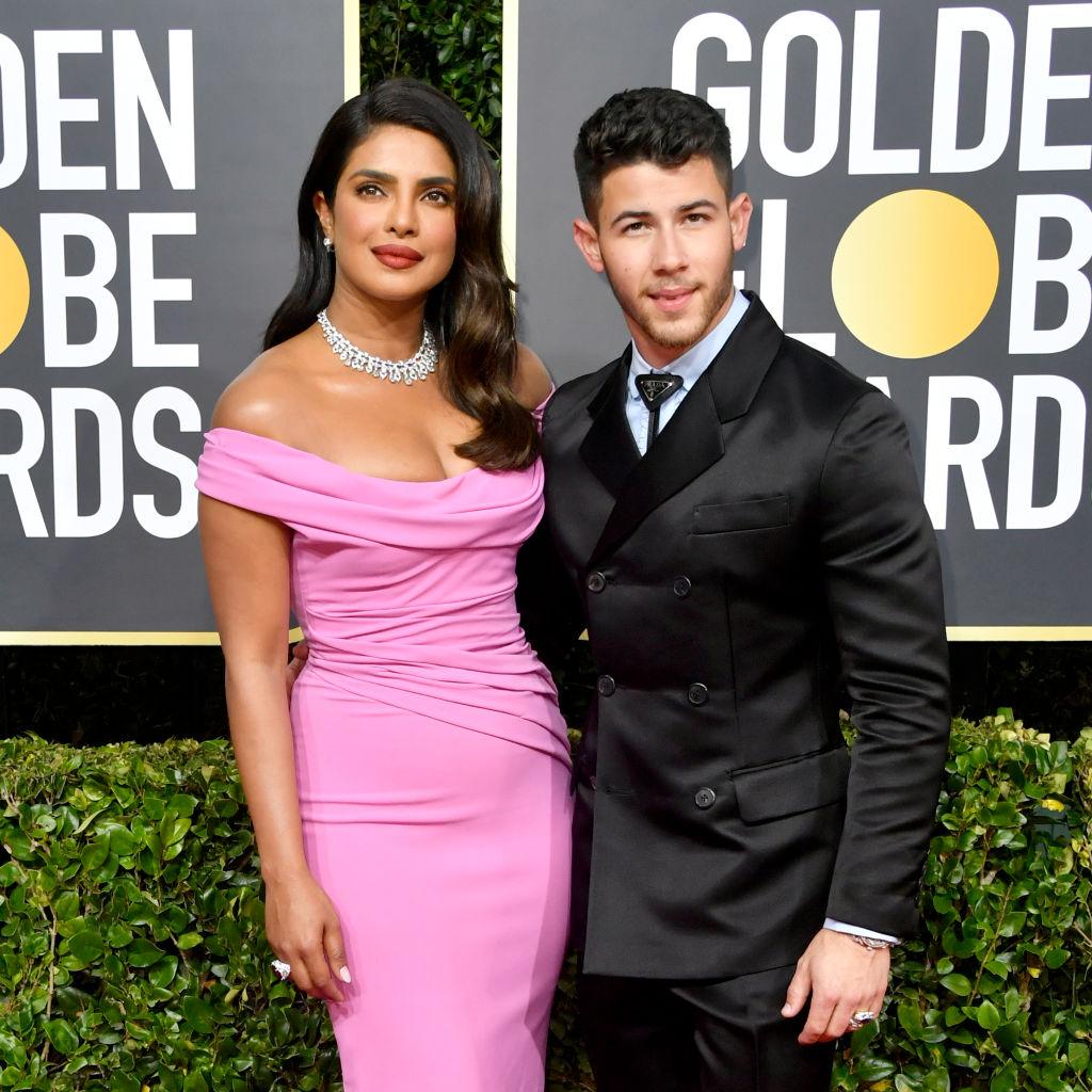 Nick Jonas și Priyanka Chopra pe covorul rosu, ea poarta o rochie roz, el costum ngru