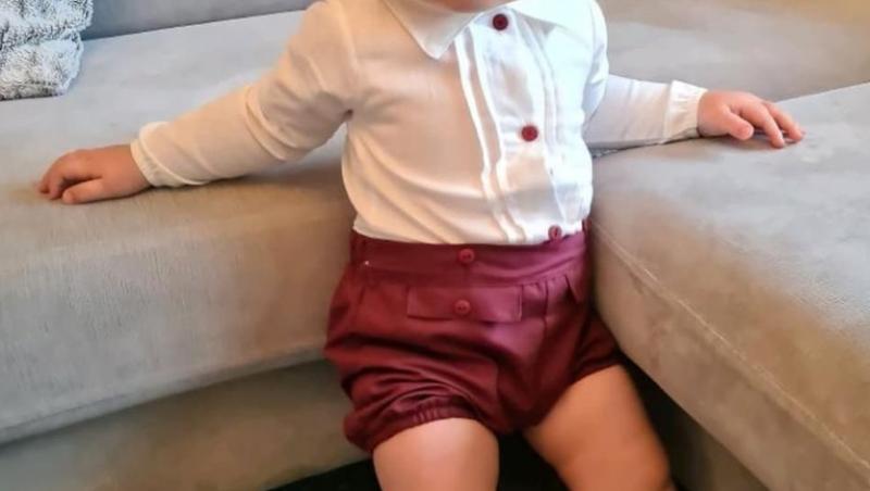 Reign Butler, la vârsta de un an și trei luni, îmbrăcat în pantaloni scurți roșii și bluză albă