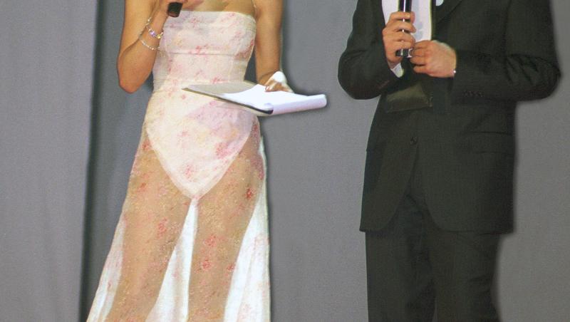 Mihaela Rădulescu, purtând o rochie albă, transparentă în partea de jos, alături de Andi Moiescu, îmbrăcat la costum