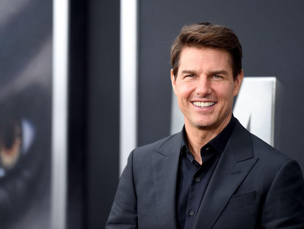 Tom Cruise, imbracat la costum, zambitor