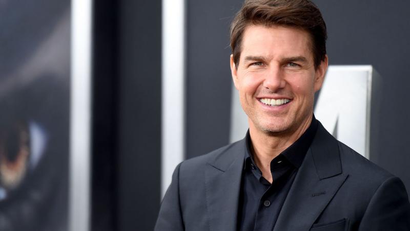 Tom Cruise, imbracat la costum, zambitor
