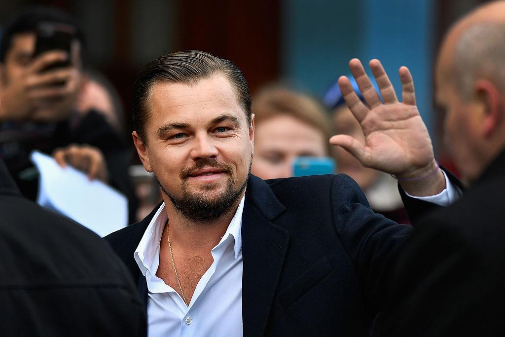 Leonardo diCaprio, imbracat la costum, face cu mana care camera