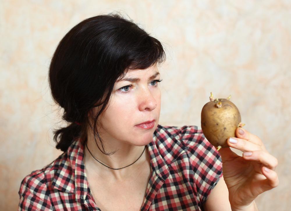 femeie care se uita urat la un cartof incoltit