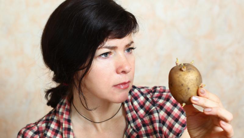 femeie care se uita urat la un cartof incoltit