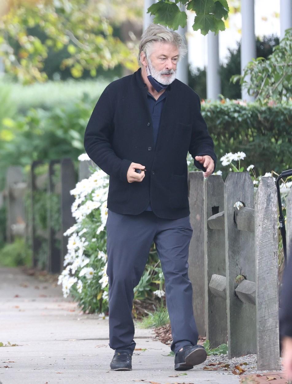 alec baldwin intr-un cardigan negru si pantaloni albastri