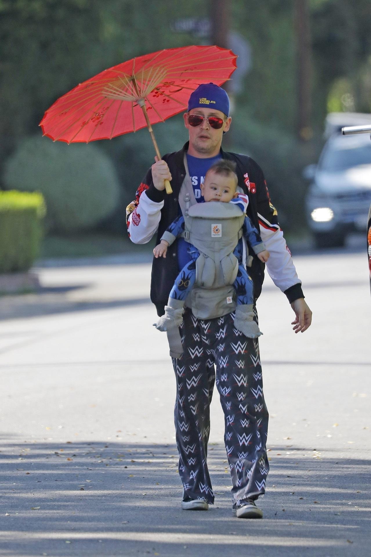 macaulay culkin, pe stradă, cu fiul lui, dakota. are o umbrelă asiatică portocalie