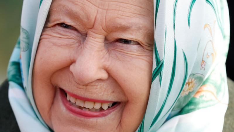 Regina Marii Britanii îmbrăcată într-o bluză neagră și cu capul acoperit de un batic alb cu printuri verzi
