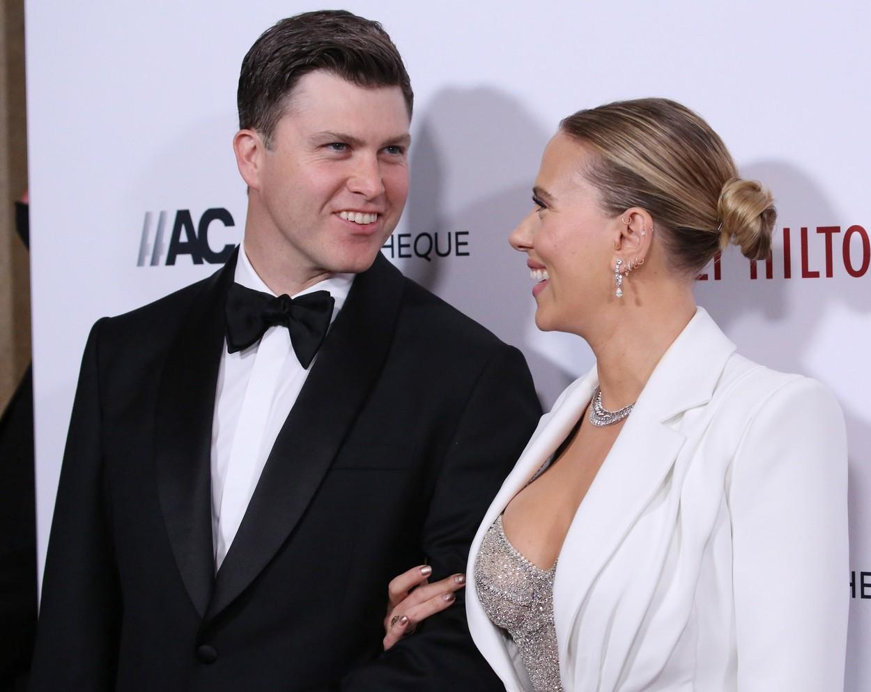 Scarlett Johansson si sotul ei se privesc si isi zambesc indragostiti, pe covorul rosu, unde ea este imbracat intr-un costum alb si el poarta un costum negru.