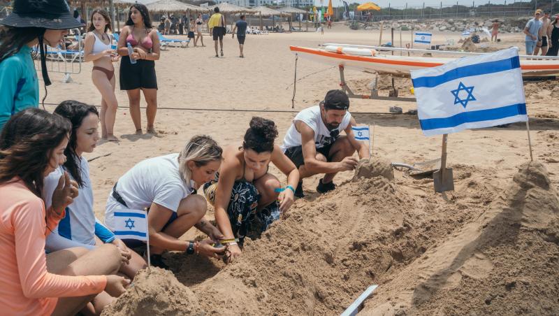 oameni facand castele de nisip pe o plaja