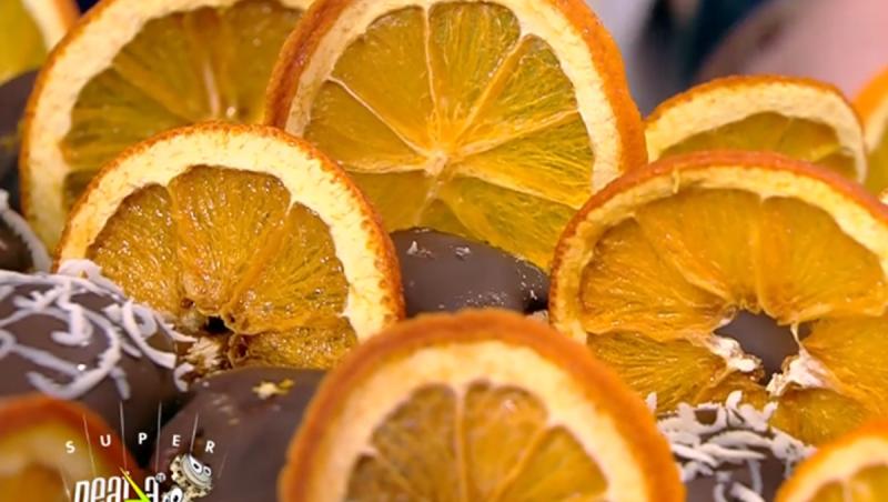 Mini eclerele și feliile de portocale se înfig în frișca de deasupra tortului
