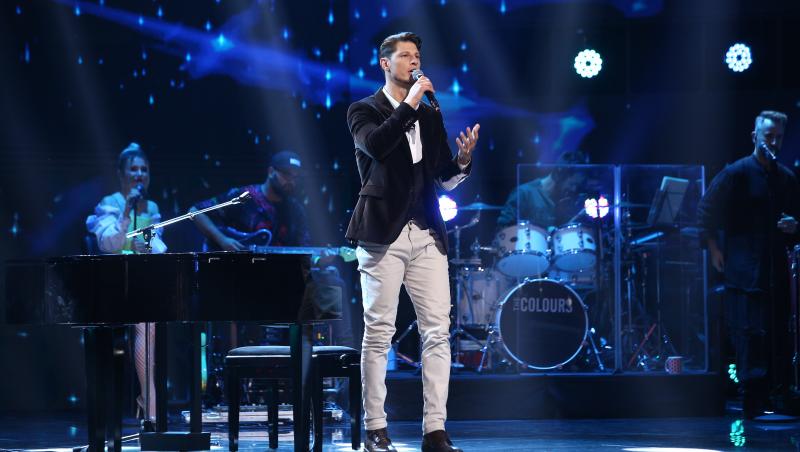 nick casciaro, etapa de battles 2, pe scena X Factor 2021. Fundal albastru, pantaloni albi, sacou maro