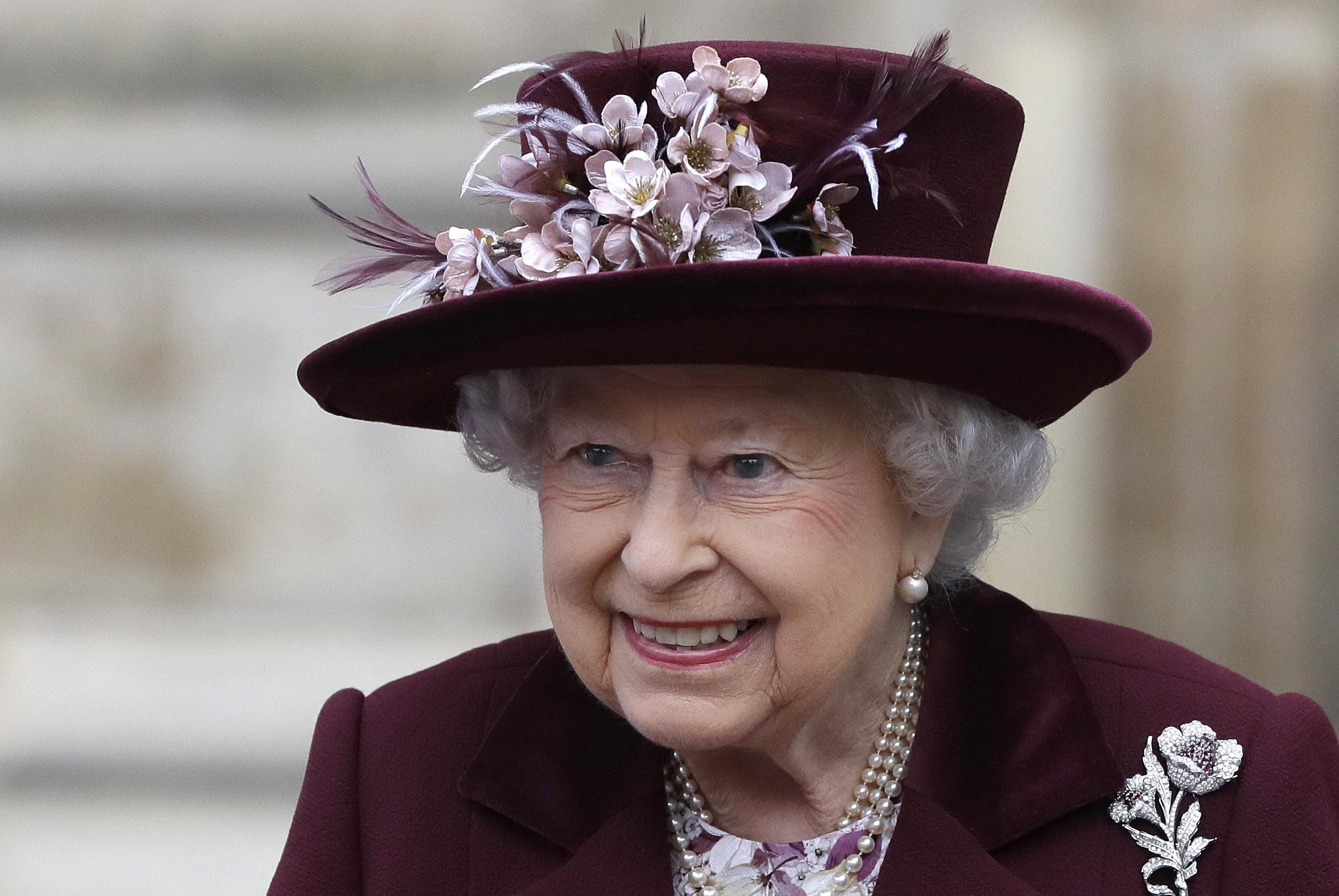 Regina Elisabeta a Marii Britanii imbracata elegant, in costum negru si cu palarie neagra