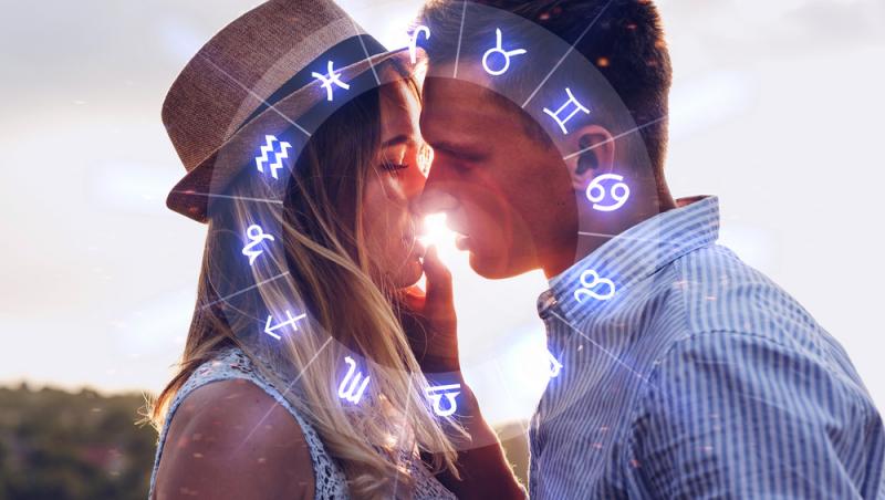 cuplu care se saruta langa o roata cu cele 12 zodii ale horoscopului