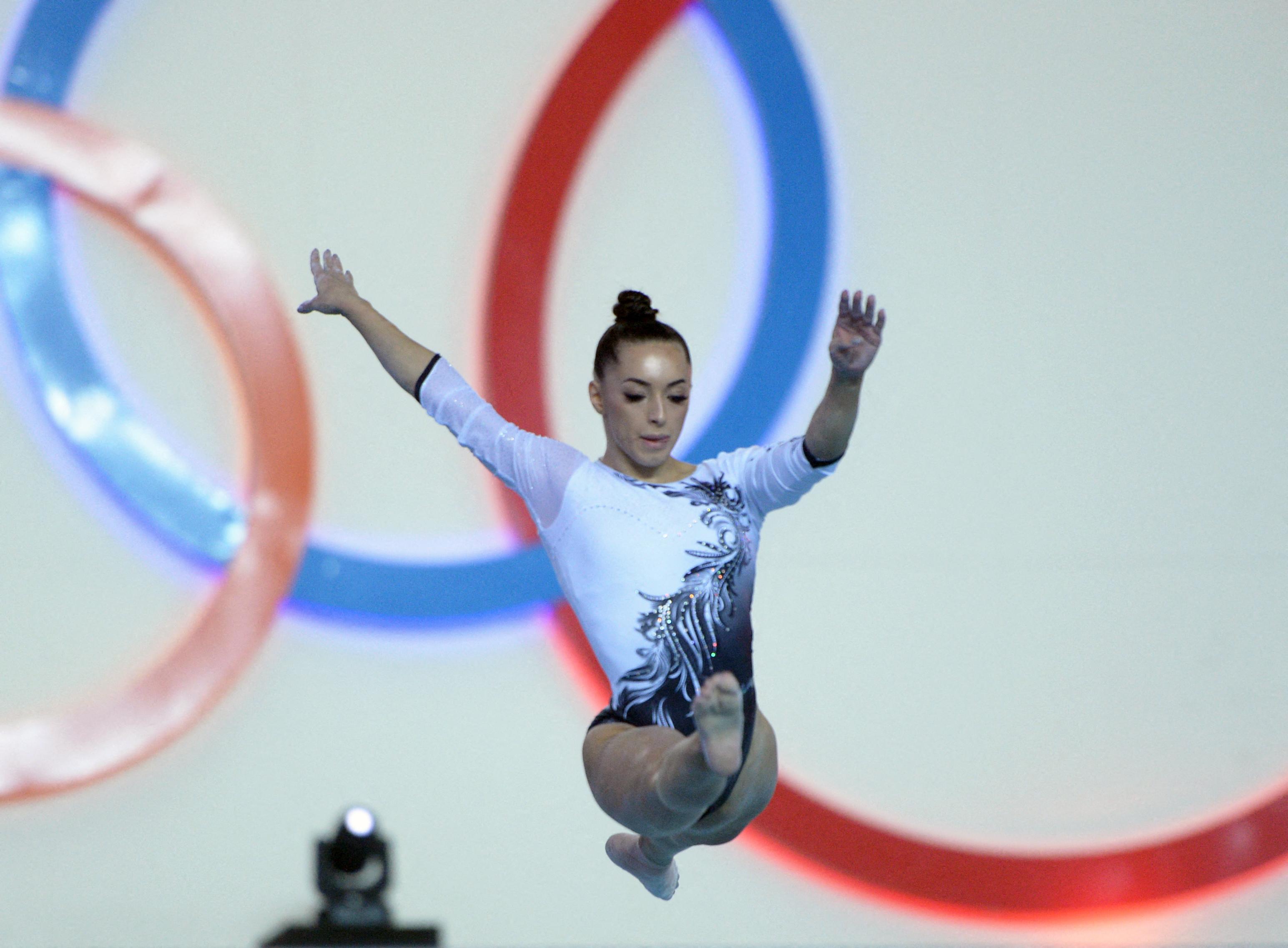 Larisa Iordache, executând un exercițiu de gimnastică, purtând un costum alb