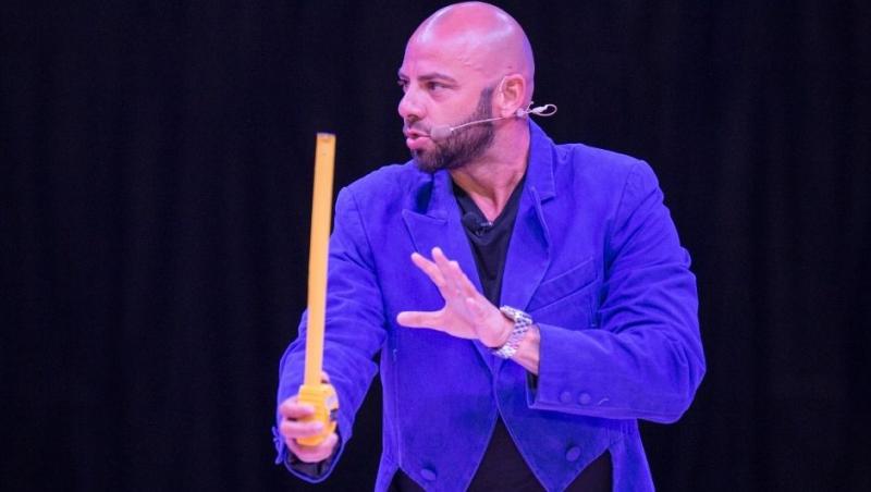 Giani Kiriță intr-un sacou albastru pe scena circului Bellucci și tine o ruleta in mana