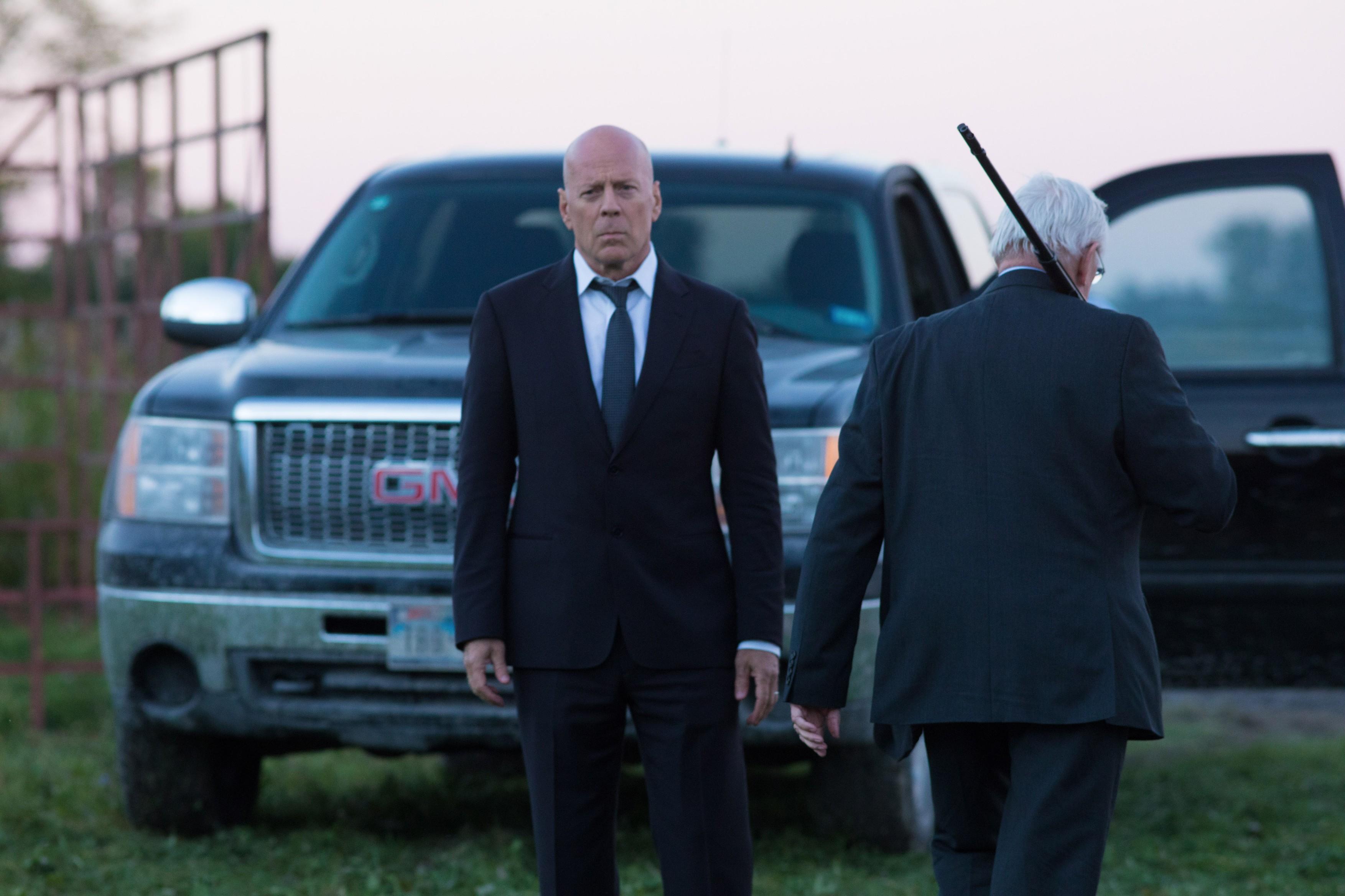 Bruce Willis, Death Wish, imbracat in negru, masina in spate