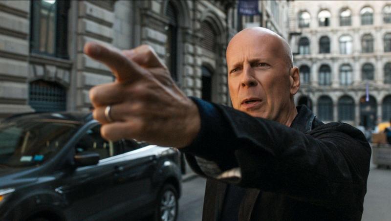 Bruce Willis, Death Wish, imbracat in negru, strada, degetul scos