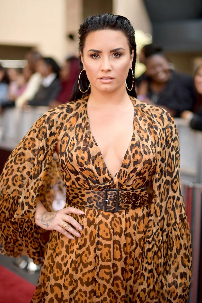 Demi Lovato într-o rochie cu imprimeu de leopard, cu părul pe spate și cercei mari