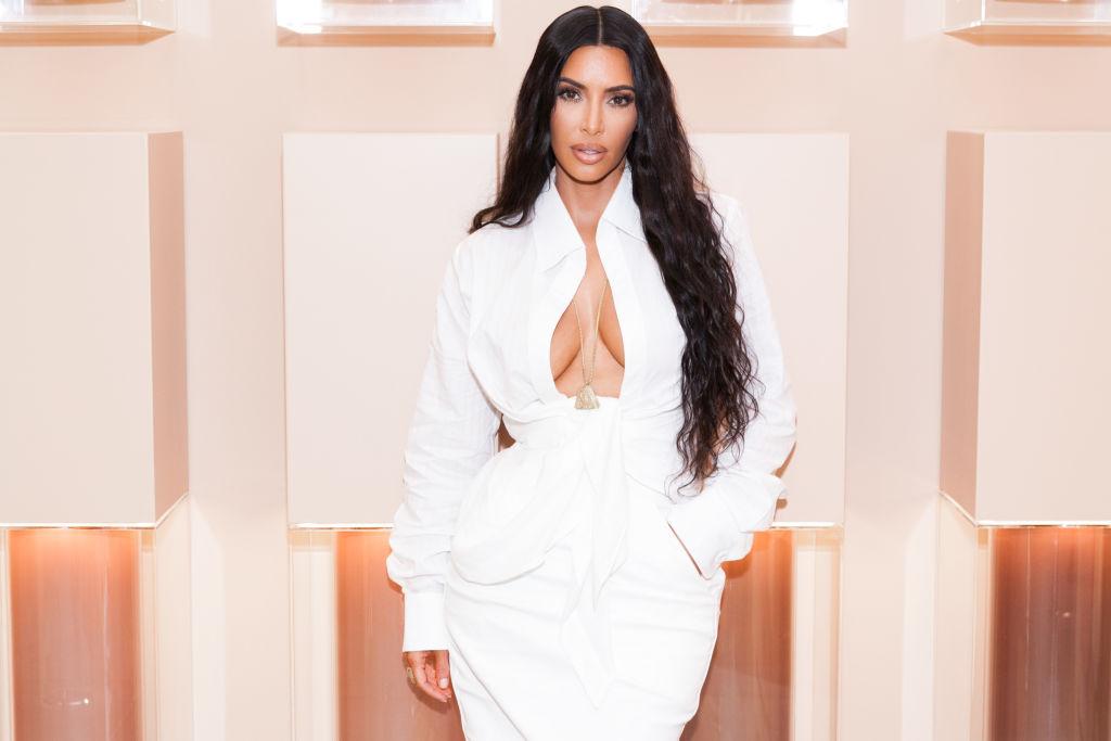 Kim Kardashian imbracata intr-o rochie alba, mulata si cu decolteul la vedere