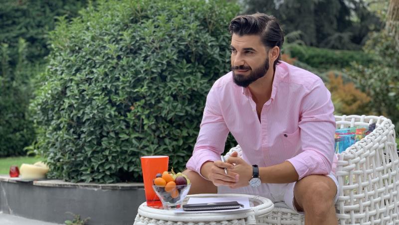 Andi Constantin într-o cămașă roz, stă la masă